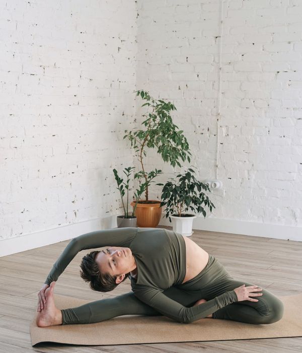 Woman in a calm yoga pose in a room with green plants.